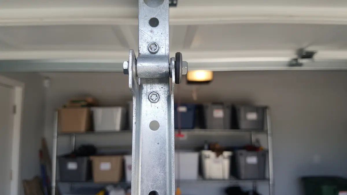 A close-up shows a metal garage door roller and hinge.